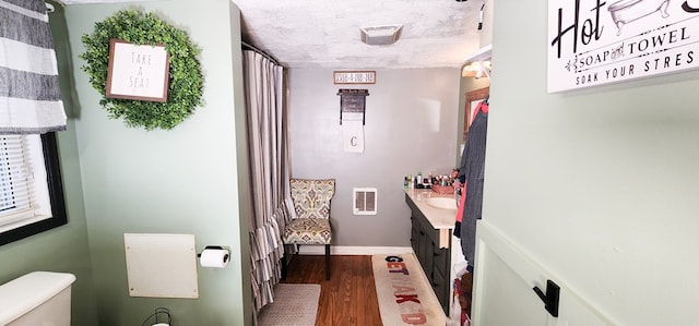 bathroom with hardwood / wood-style flooring, vanity, toilet, and a textured ceiling