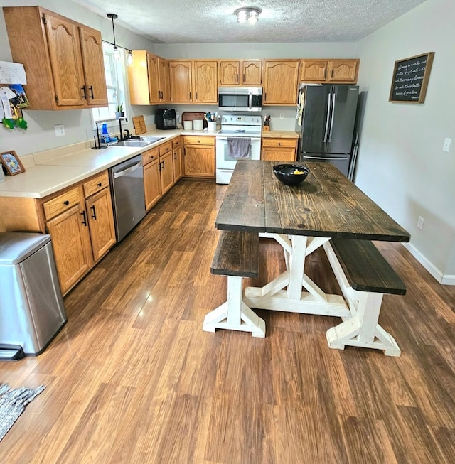 kitchen with a sink, dark wood-style flooring, light countertops, a textured ceiling, and stainless steel appliances