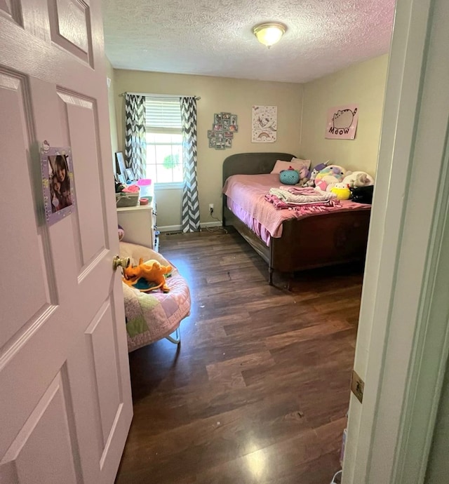 bedroom with baseboards, wood finished floors, and a textured ceiling