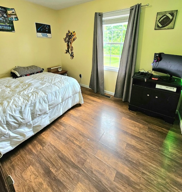 bedroom with visible vents, baseboards, and wood finished floors