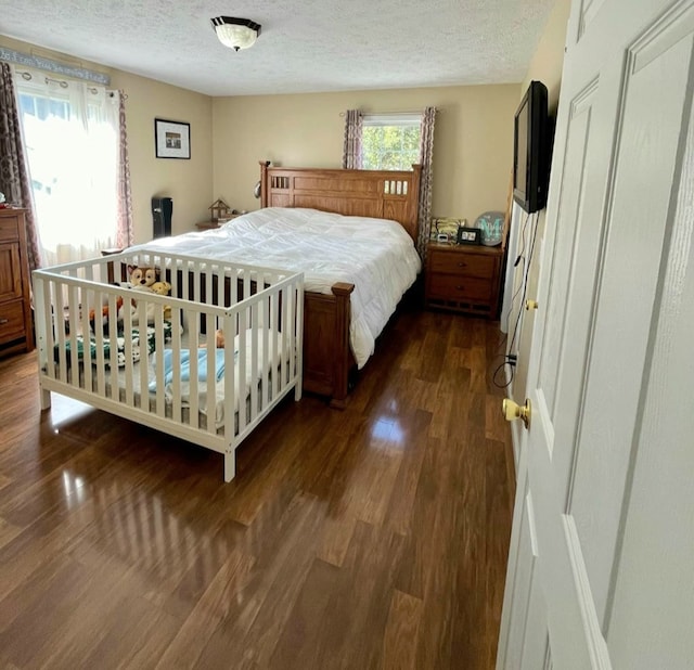 bedroom with a textured ceiling and dark wood-style flooring