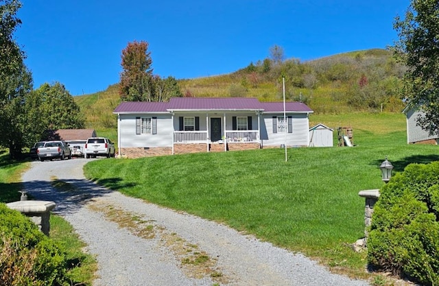 view of front of house with a front yard, a mountain view, a porch, metal roof, and gravel driveway