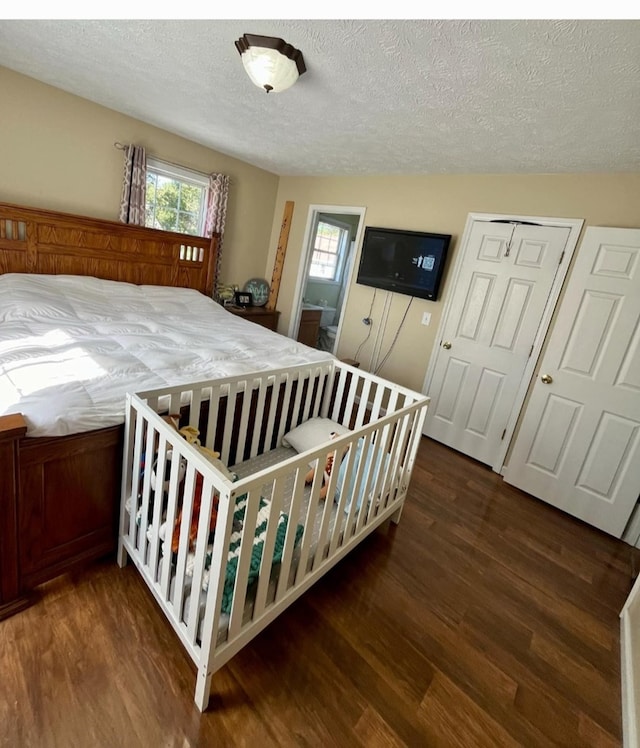 bedroom featuring a textured ceiling, wood finished floors, and multiple windows