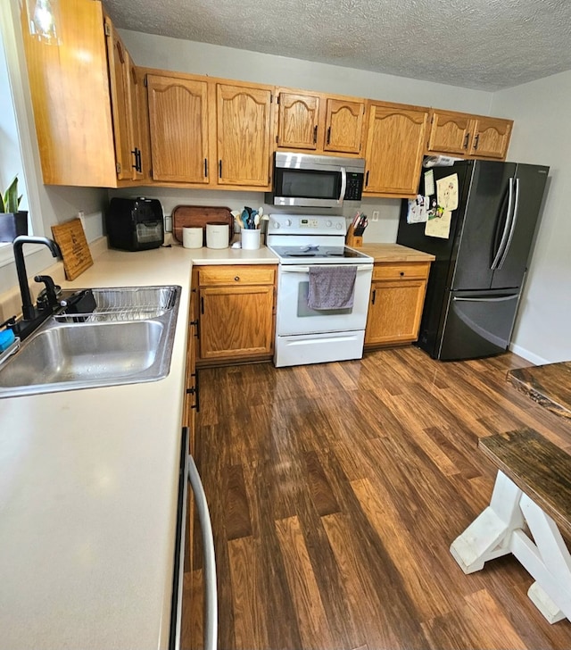 kitchen with stainless steel microwave, dark wood-style floors, freestanding refrigerator, white electric range, and a sink