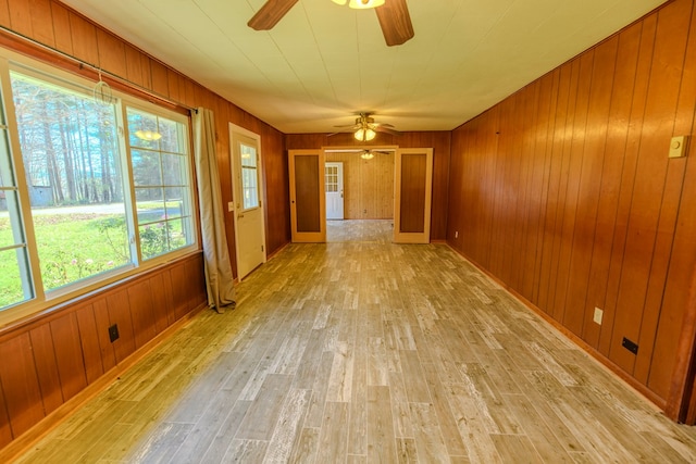 spare room with wood walls, ceiling fan, and light hardwood / wood-style flooring