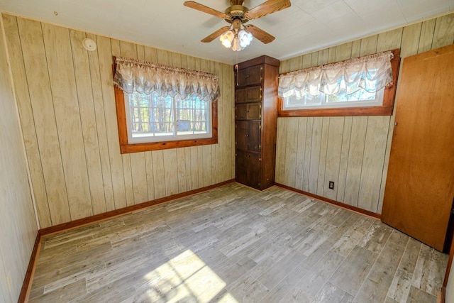 unfurnished bedroom featuring ceiling fan, wooden walls, and light wood-type flooring