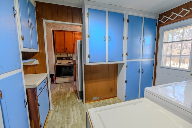 interior space featuring washer / dryer, stainless steel refrigerator, wooden walls, electric stove, and light hardwood / wood-style floors