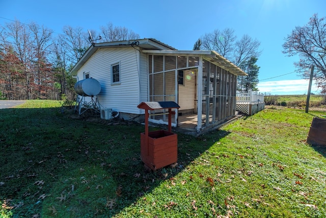 view of side of property featuring a lawn and a sunroom