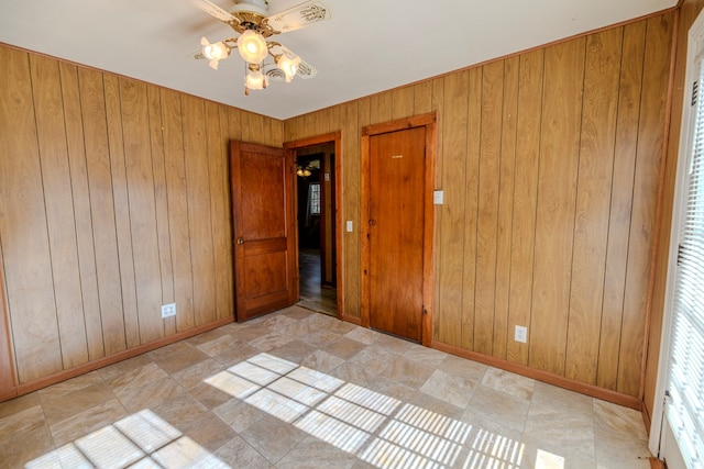 unfurnished bedroom featuring wooden walls and ceiling fan