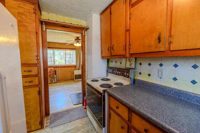 kitchen with tasteful backsplash, a textured ceiling, wooden walls, white appliances, and light hardwood / wood-style floors