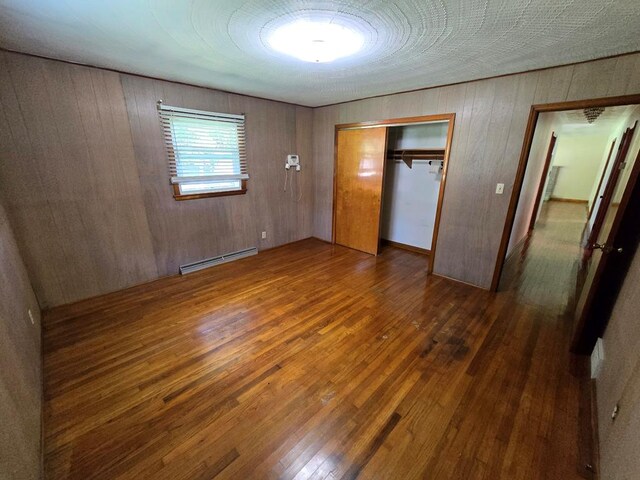 128 Roberts Chapel Rd, Saltville, VA 24370 - unfurnished bedroom with a baseboard radiator, wood-type flooring, a closet, and wood walls