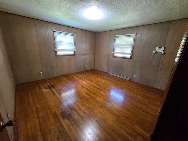 128 Roberts Chapel Rd, Saltville, VA 24370 - empty room featuring a baseboard radiator, wood finished floors, healthy amount of natural light, and wooden walls