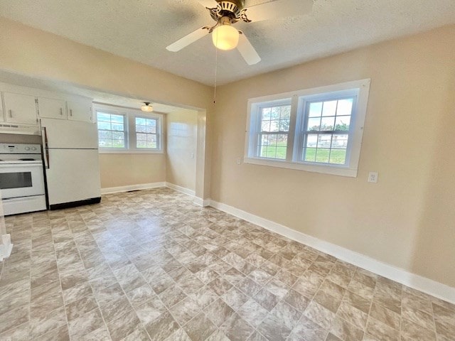 kitchen with ceiling fan, white appliances, plenty of natural light, and white cabinets