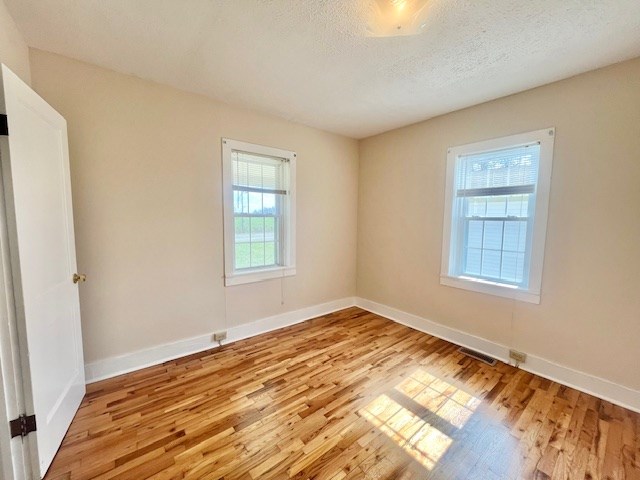 spare room with a textured ceiling and light wood-type flooring