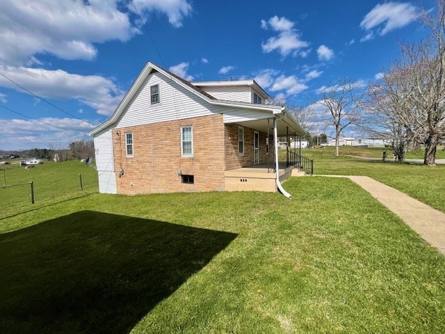 rear view of house featuring a lawn and a porch