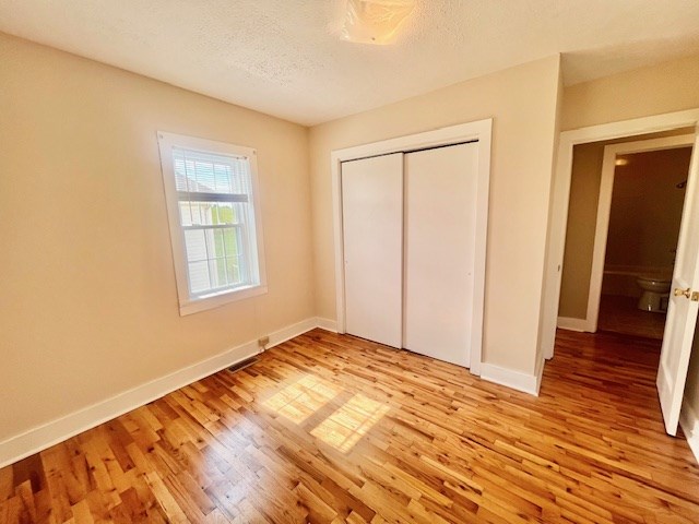 unfurnished bedroom with light hardwood / wood-style floors, a closet, and a textured ceiling