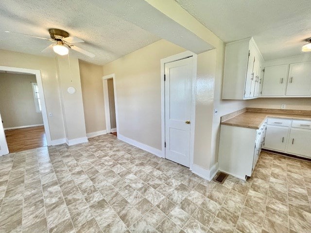 kitchen featuring white cabinetry, a textured ceiling, and ceiling fan