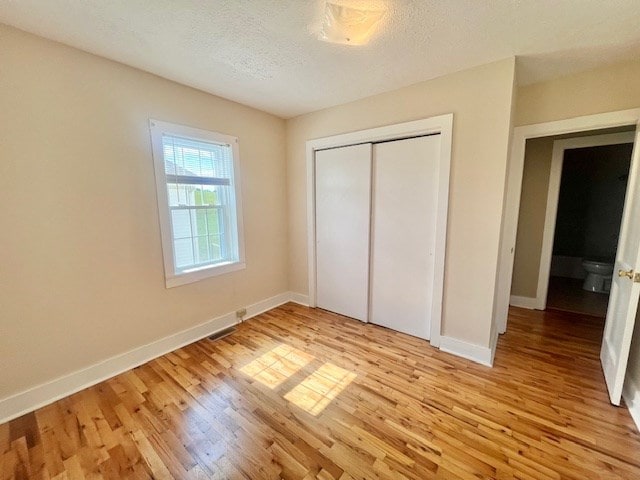 unfurnished bedroom with a textured ceiling, light hardwood / wood-style floors, and a closet