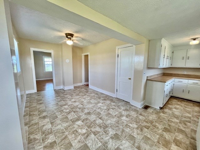 kitchen featuring ceiling fan, a textured ceiling, and white cabinets