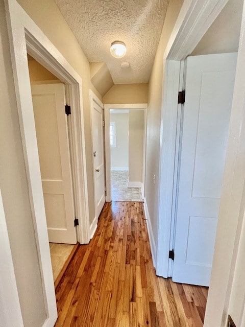 hall featuring light hardwood / wood-style flooring and a textured ceiling