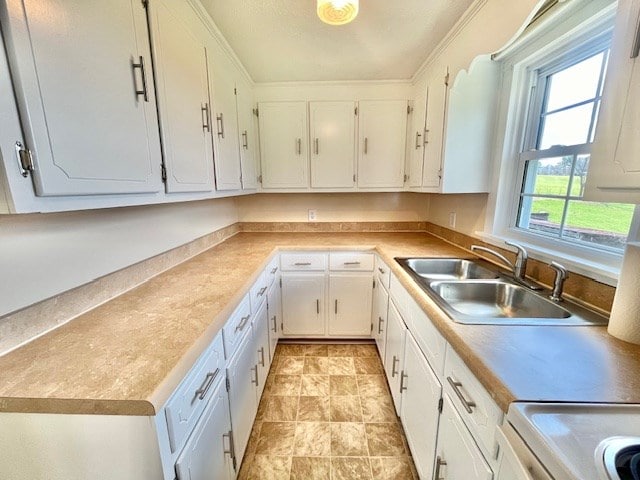 kitchen with white cabinetry, ornamental molding, range, and sink