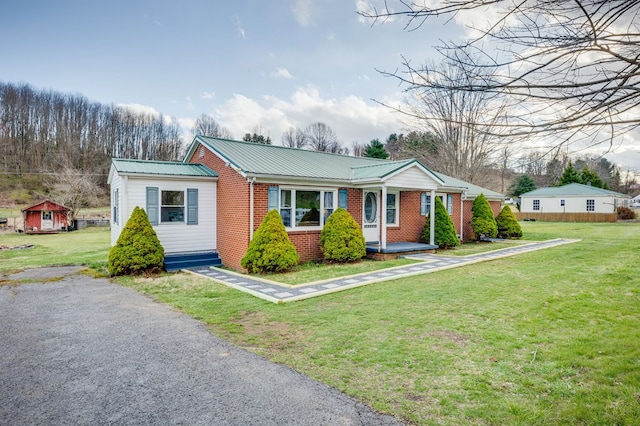 view of front of house featuring brick siding, a front lawn, and metal roof