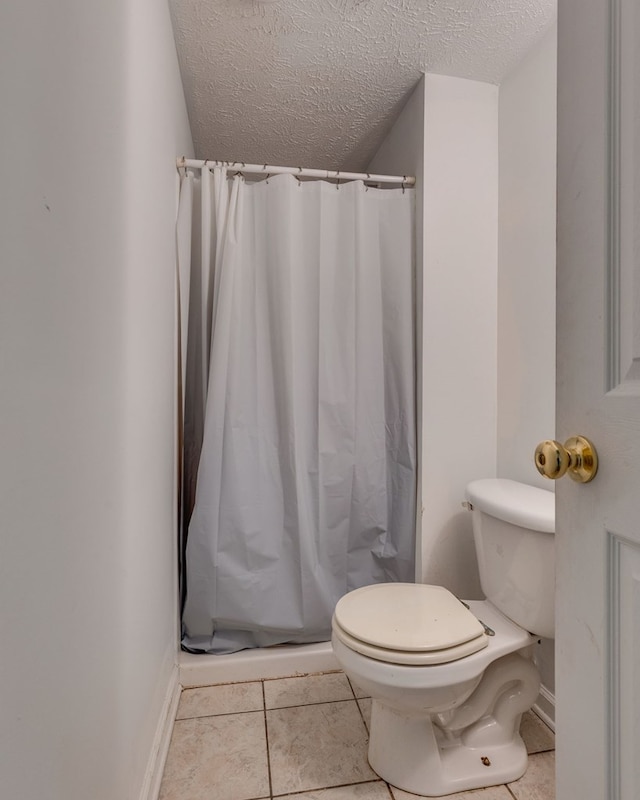 bathroom featuring a textured ceiling, toilet, and a stall shower