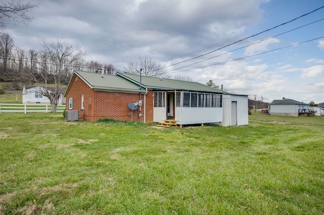 back of property featuring a sunroom, entry steps, a yard, and central AC