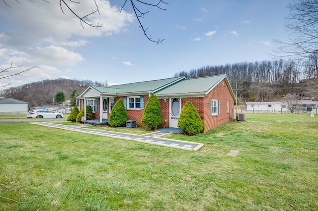view of front of home featuring central air condition unit, a front lawn, and metal roof