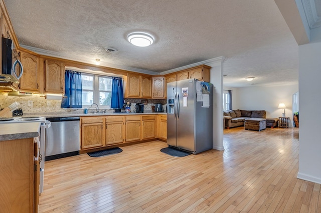 kitchen featuring a sink, light wood-style floors, appliances with stainless steel finishes, and tasteful backsplash