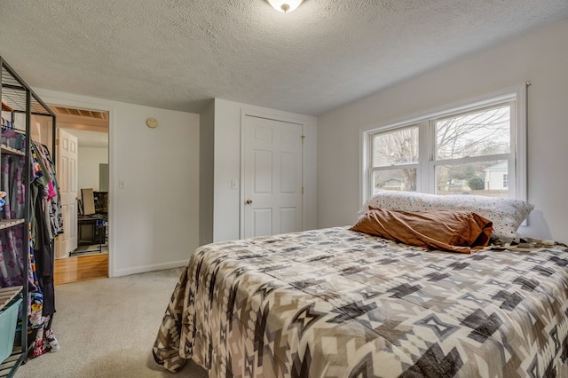 bedroom with light carpet, a textured ceiling, visible vents, and baseboards