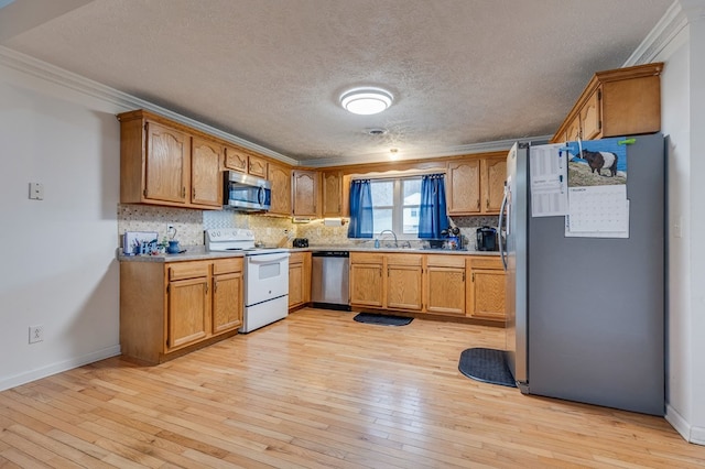 kitchen featuring backsplash, crown molding, light wood-type flooring, and appliances with stainless steel finishes