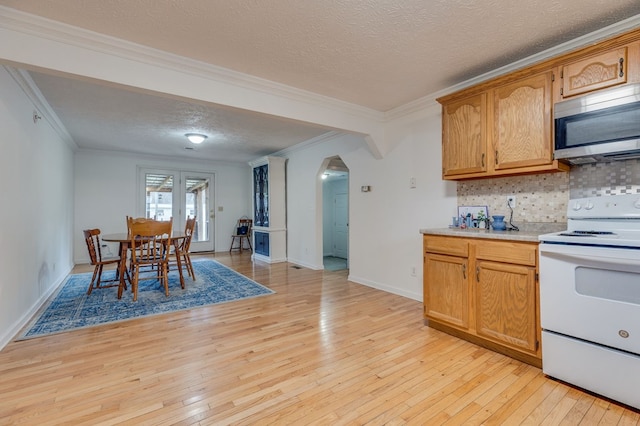 kitchen with stainless steel microwave, arched walkways, white electric range, and light wood-style flooring