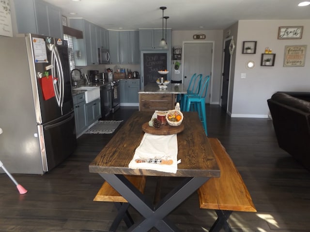 kitchen with sink, a center island, hanging light fixtures, appliances with stainless steel finishes, and dark hardwood / wood-style flooring