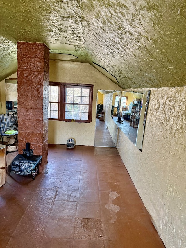 corridor with a textured wall and vaulted ceiling