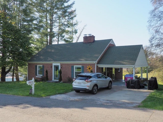new england style home featuring a chimney, a front yard, brick siding, concrete driveway, and a shingled roof