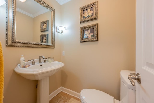 bathroom featuring toilet, baseboards, and crown molding