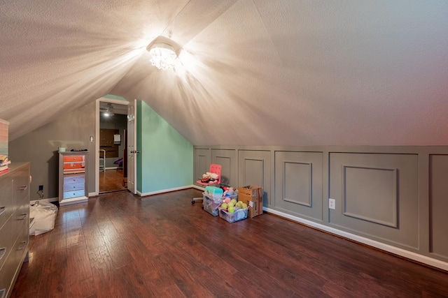 bonus room featuring a textured ceiling, vaulted ceiling, hardwood / wood-style flooring, and a decorative wall