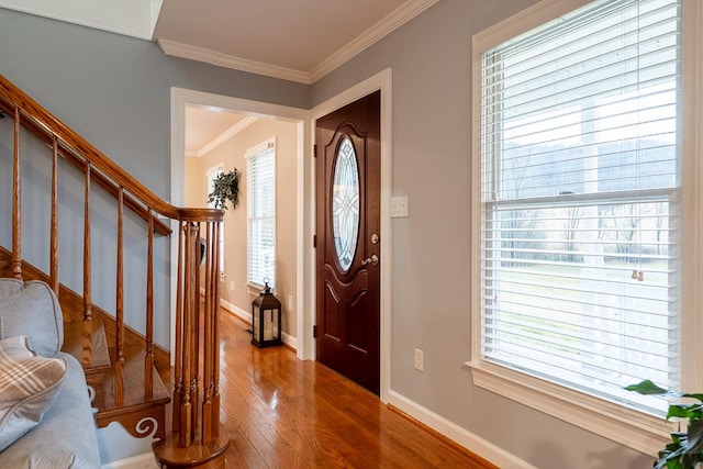 entrance foyer featuring baseboards, stairs, ornamental molding, and wood finished floors