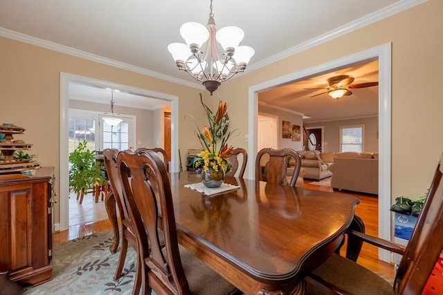 dining area featuring ceiling fan with notable chandelier, crown molding, and wood finished floors