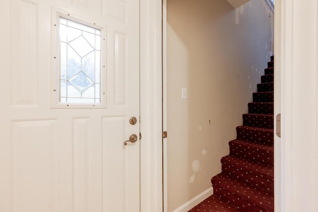 entrance foyer featuring carpet floors, stairway, and baseboards