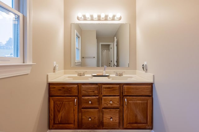 bathroom featuring a healthy amount of sunlight, double vanity, and a sink