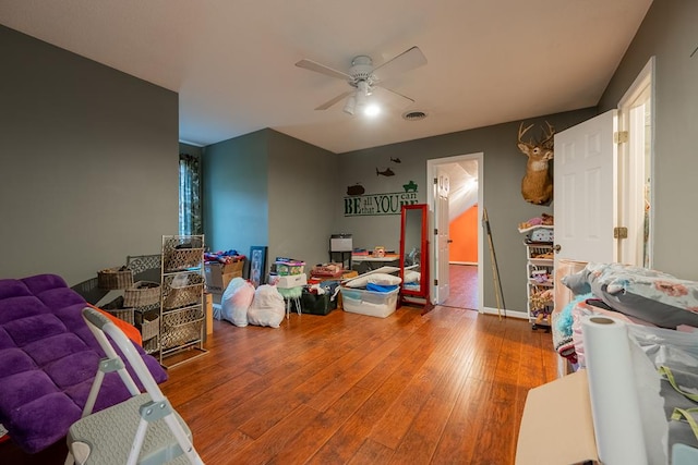 rec room featuring hardwood / wood-style flooring, ceiling fan, visible vents, and baseboards