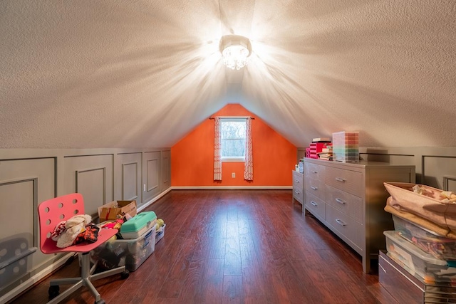 additional living space with a textured ceiling, vaulted ceiling, and dark wood-type flooring