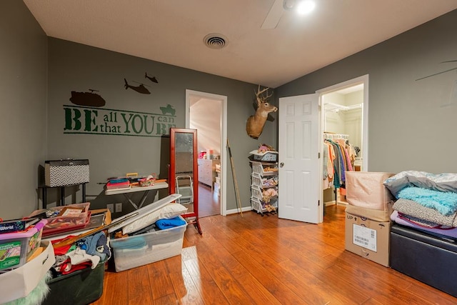 bedroom featuring a closet, visible vents, a spacious closet, hardwood / wood-style floors, and baseboards