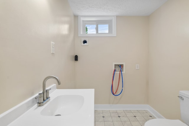 bathroom with baseboards, toilet, a sink, and a textured ceiling