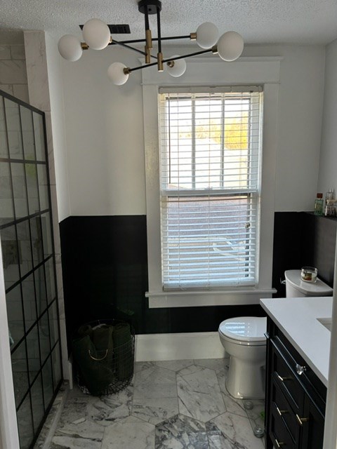 bathroom with vanity, tiled shower, a textured ceiling, and toilet