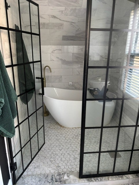 bathroom with tile patterned flooring and a bath