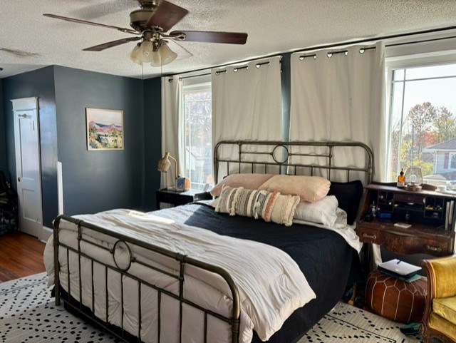 bedroom with a textured ceiling, ceiling fan, and light wood-type flooring