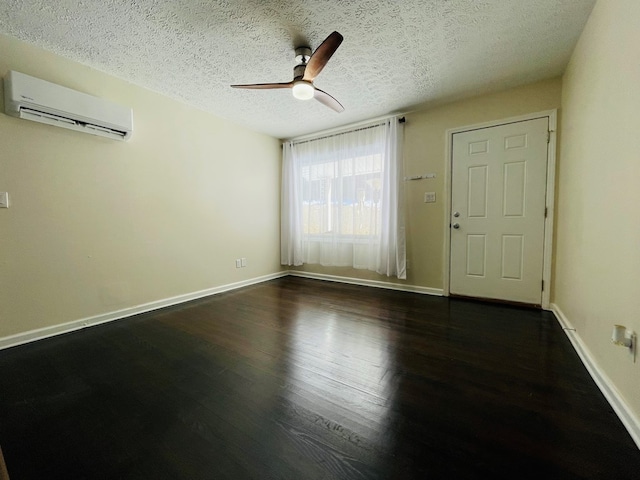 empty room featuring ceiling fan, dark hardwood / wood-style floors, a wall mounted AC, and a textured ceiling